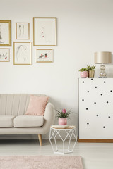 Cropped photo of the sofa, modern coffee table, paintings and lamp in a sweet living room interior