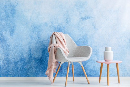 Blanket on an armchair and coffee table with a white vase set on an ombre wall. Place your product