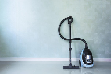 Vacuum cleaner on white concrete background in the house.