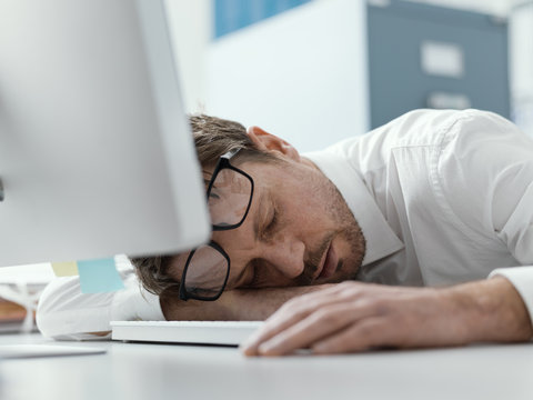 Exhausted business executive sleeping on his desk