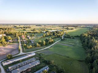 drone image. asphalt road surrounded by pine forest and fields from above