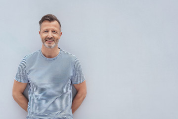 Friendly middle-aged man posing against a wall