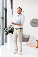 Full length photo of attractive modern man wearing eyeglasses looking at camera, while standing and...