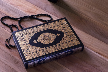 Holy islamic book Quran on the wodden board with a rosary - Ramadan kareem/Eid al fitr Concept.