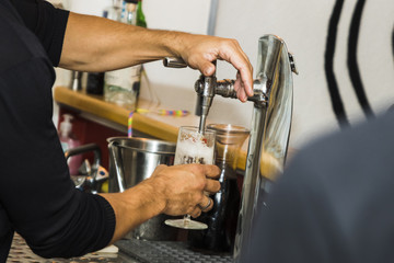 Bartender pouring fresh cold beer from tap