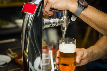 Fototapeta na wymiar Bartender pouring fresh cold beer from tap