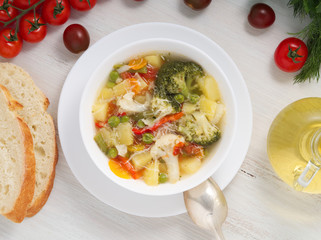 Minestrone soup. Vegetable soup with tomato, celery, carrot, zucchini, onion, pepper, broccoli. Top view, white backdrop