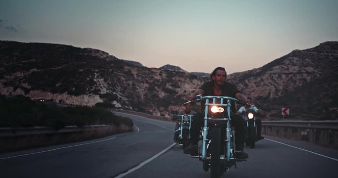 Young rebel men riding motorcycles on mountain road trip