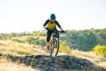 Plakat Cyclist Riding the Mountain Bike on the Summer Rocky Trail at the Evening. Extreme Sport and Enduro Cycling Concept.