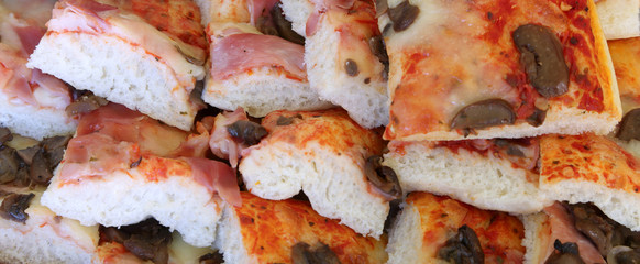 slices of pizza with ham and mushrooms in a take-away pizzeria