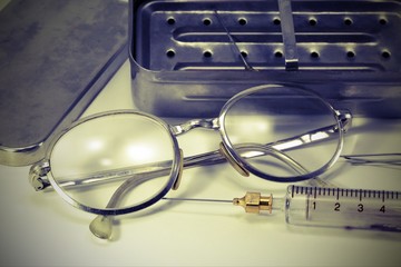 syringe in fragile glass with steel needle and the glasses of th