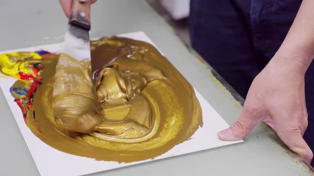 man mixes paint until golden in color, to print logo on packaging products