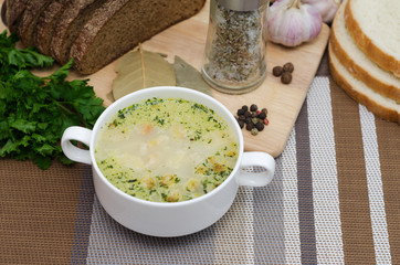 Mushroom soup with croutons in a white dish is on a wooden table.