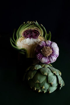 Close up of artichoke and garlic against black background