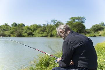 Senior fisherman catches a fish in the river at the bait