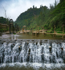 Bamboo bridge behind a waterfall