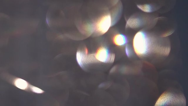 Abstract bokeh holiday background. Decoration of playing colored light. Christmas and new year iridescent lights on dark background. Rainbow of defocused crystal bead hangings in full HD clip.
