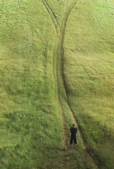 A man stands on the road before a crossroads