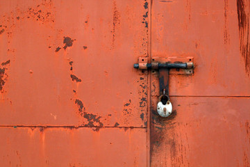 Red color old padlock on metal gate.