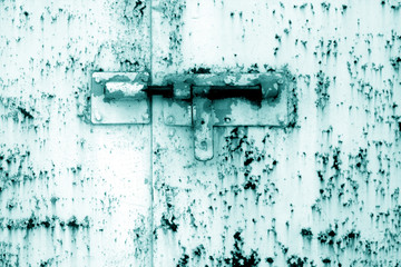 Old padlock on metal gate in cyan tone.