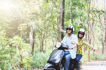 Couple riding their scooter through forest. life style idea concept