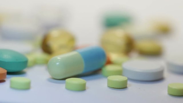 Many different medicines on white table. colorful pills, capsules and dragees