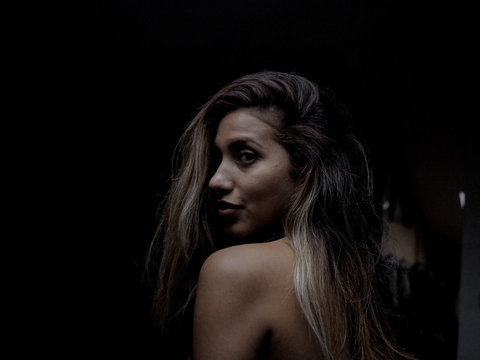 Sensual woman in darkness looking back
