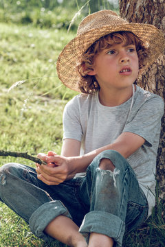 Close up of boy sitting near tree trunk