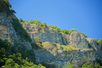 A mountain range not far from the city of Sochi. High rocks and a cliff beneath them. Eagle rocks. Green forest below.