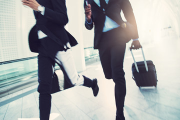 Two businessmen rushing through an airport to catch a flight