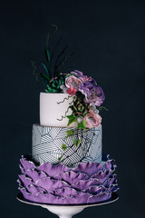 White wedding cake with purple flower detail.Purple wedding cake decorated with flowers and pearls.three layers cake with sugar paste flowers