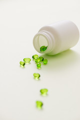 Green capsules in a bottle isolated on white background