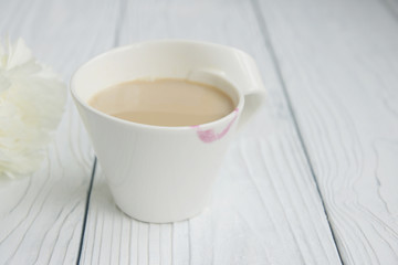 White cup of coffee on a white table with traces of lipstick