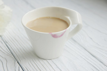 White cup of coffee on a white table with traces of lipstick
