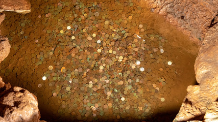 Wishing well and coins inside Grutas Mira de Aire cave in Portugal