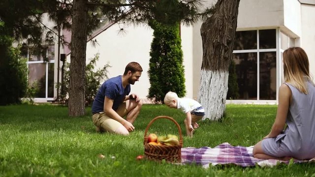 Caucasian family. Father amusing his little son, throwing cones to the air. Hanging out in the park. Picnic concept. Slow motion