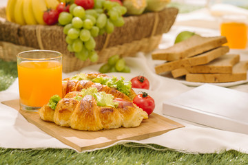 Sumptuous picnic spread out on a red and white checked cloth with wicker basket
