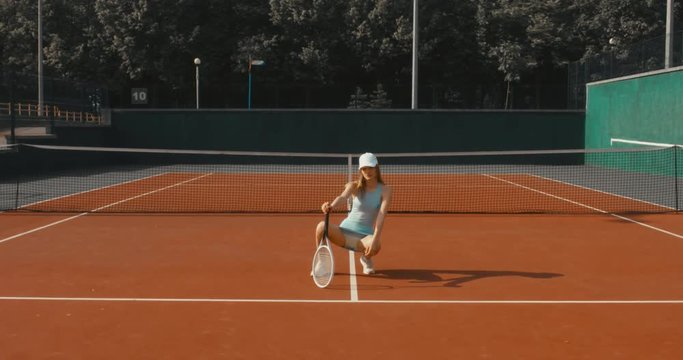 Portrait of young Caucasian teen model wearing fashionable tennis dress, posing on tennis hardcourt, summer sunny day outdoors. Fashion portrait shoot