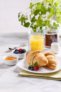 Breakfast served with croissants, coffee, orange juice and berries.