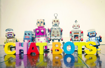the words  CHAT BOTS  with wooden letters and retro toy robots  on an old wooden floor