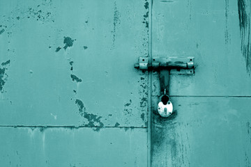 Old padlock on metal gate in cyan color.