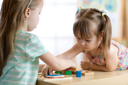 Kids playing with colorful toys. Two children girls at home or daycare centre. Educational child toys for preschool and kindergarten.