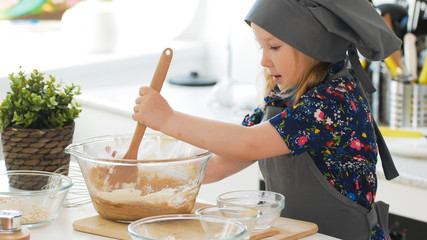 Girl baker mixes the mixture for cookies with a whisk