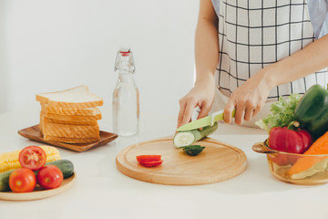Young woman cutting vegetables in kitchen