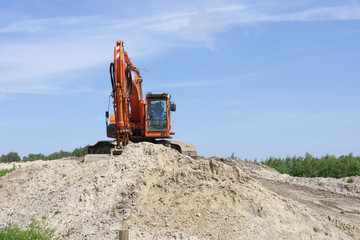 Big red crane on a high sand mountain