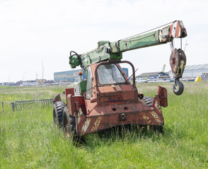 Fototapeta na wymiar Old abandoned rusty construction crane in green grass