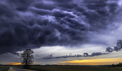 Dark dramatic landscape stormy sky over fields.