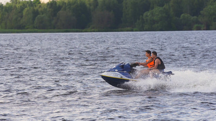 People riding on a jet ski. High speed jetski with water spray. People rid on water scooter.