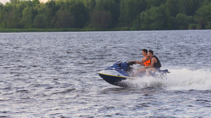 Fototapeta premium People riding on a jet ski. High speed jetski with water spray. People rid on water scooter.