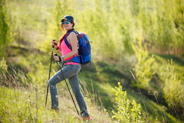 Image of smiling sportswoman with walking sticks and backpack